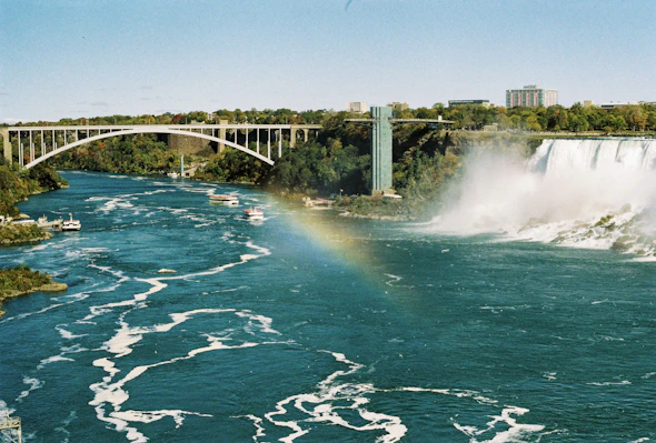 a large waterfall with a bridge in the background