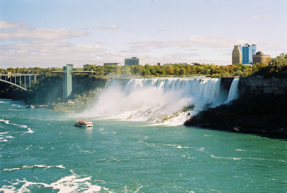 a large waterfall with a boat in the water below