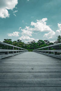 a wooden bridge with trees and blue sky