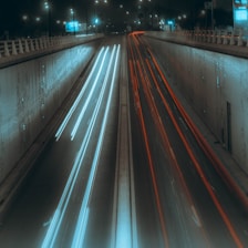 a long road with a wall and lights on either side