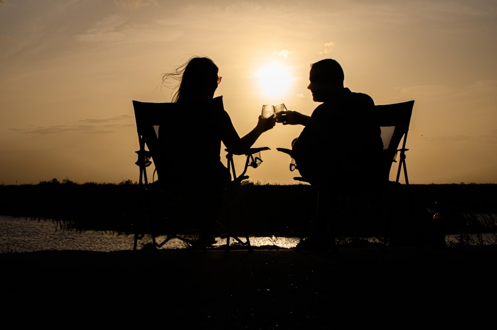 um homem e uma mulher sentados em um banco ao pôr do sol