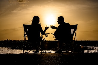 a man and woman sitting on a chair at the beach
