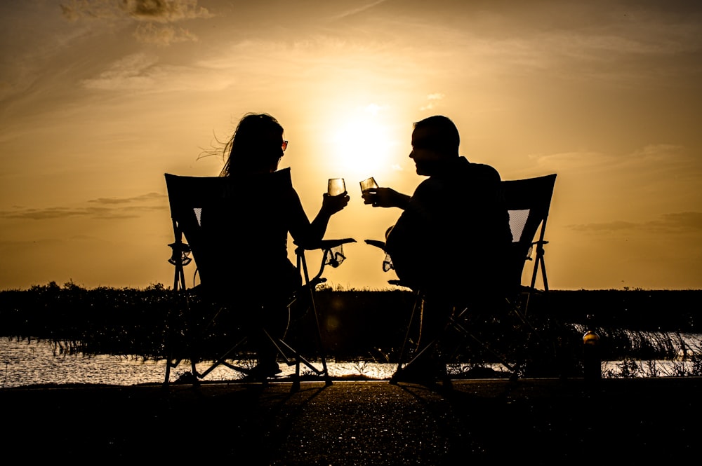 a man and woman sitting on a chair at the beach