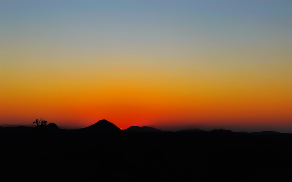 a silhouette of a mountain and a sunset