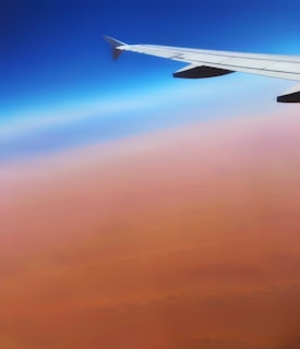 Scenic view of an airplane taking off over Egyptian desert landscape during sunset.