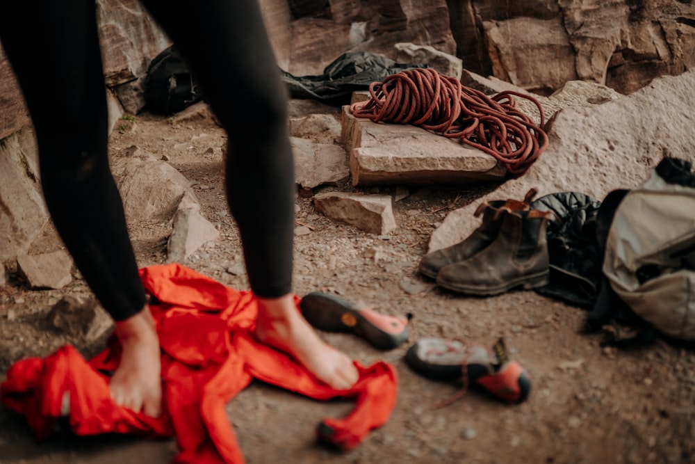 a person's feet on a red blanket next to a pile of shoes