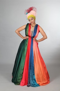 Regal Rhythm in a dramatic John Galliano-inspired gown with subtle rainbow accents under soft stage lighting.