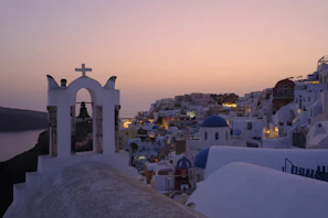 A serene early morning shot of Santorini’s blue domes glowing softly against a pale sky
