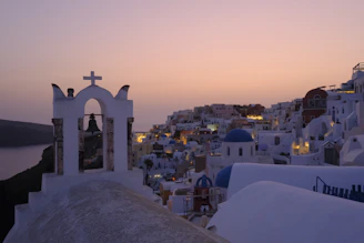 A serene early morning shot of Santorini’s blue domes glowing softly against a pale sky