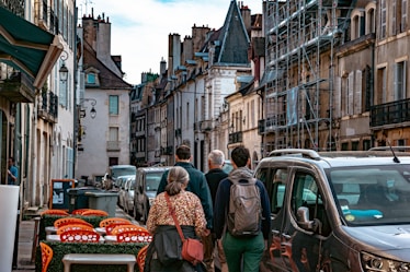 a group of people walking down a street lined with parked cars