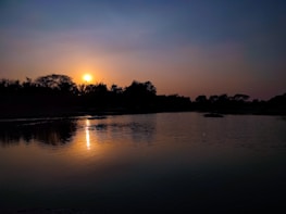 A peaceful sunset over a calm lake, reflecting warm colors.