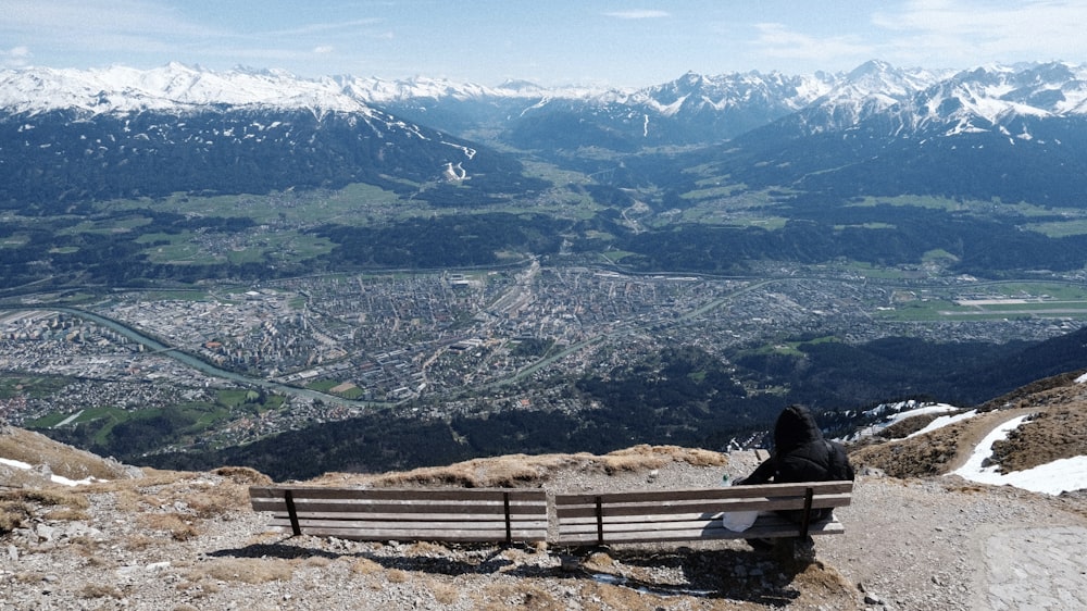 a person sitting on a bench overlooking a mountain range