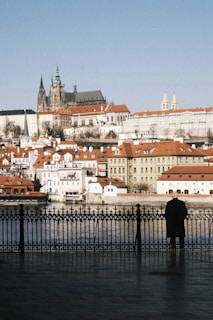 a person standing on a bridge over water with buildings in the background
