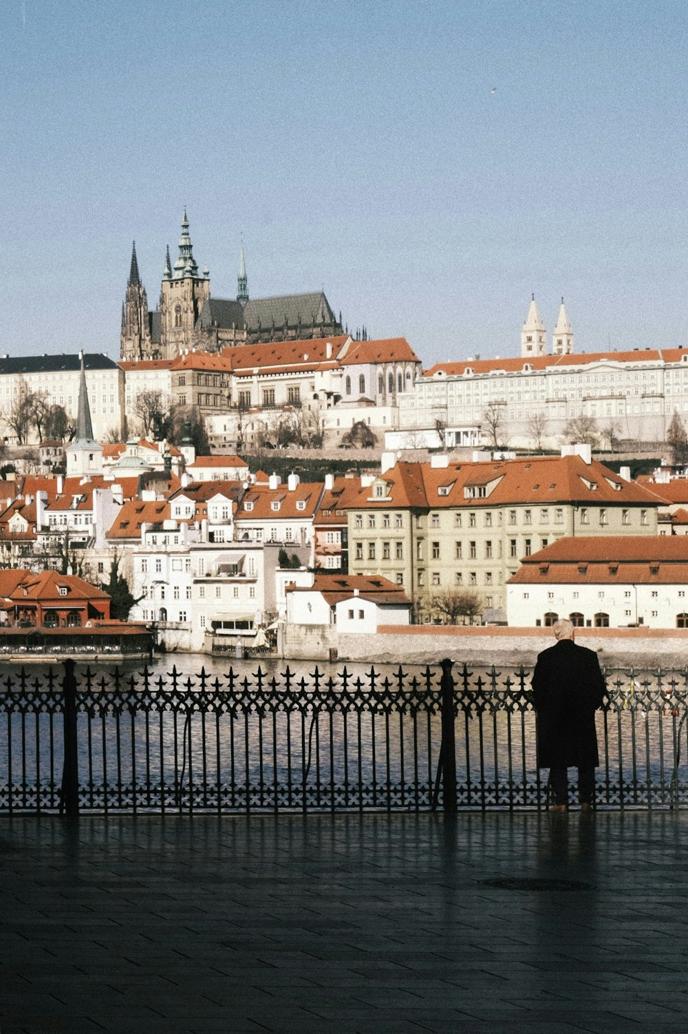 a person standing on a bridge over water with buildings in the background