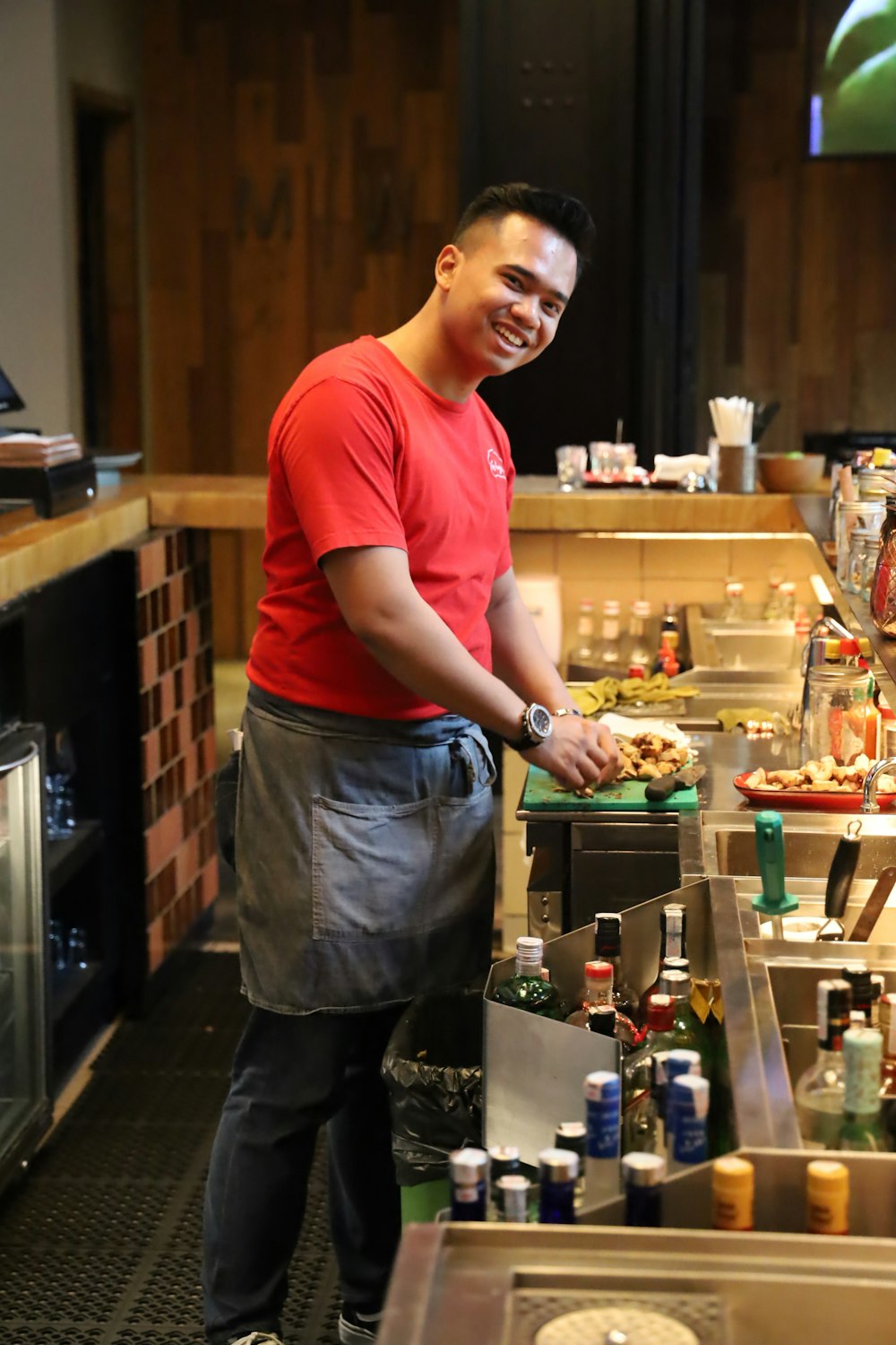 a person smiling and standing in a kitchen