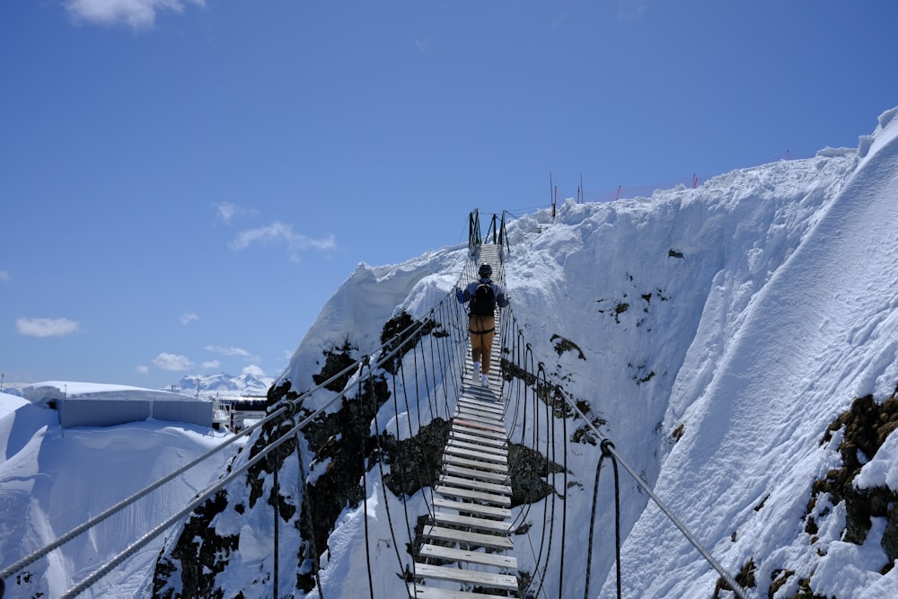 une personne grimpant sur une échelle sur une montagne enneigée