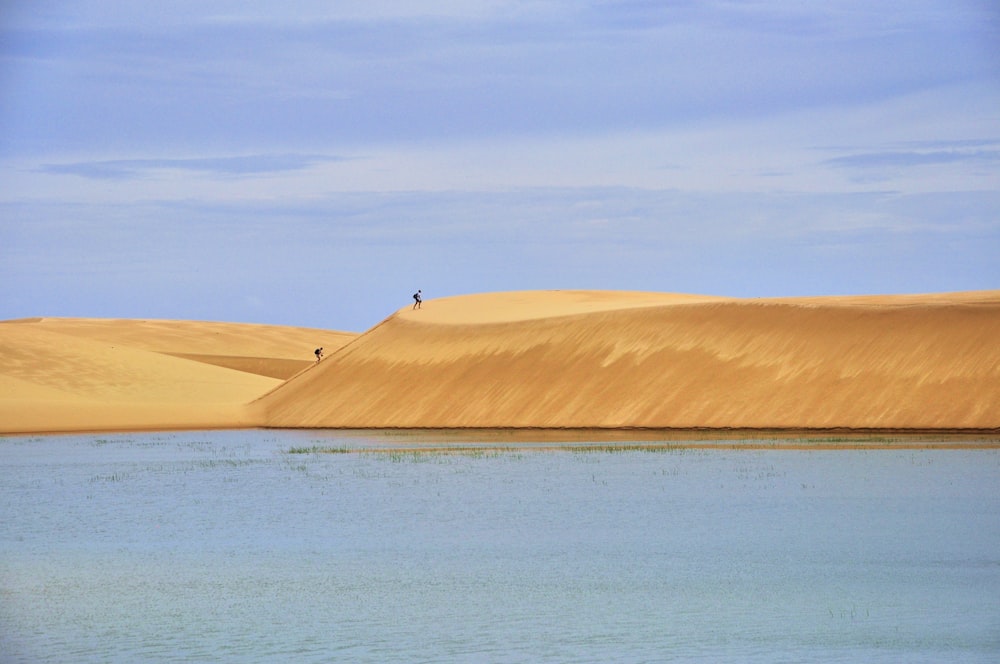 Una persona parada en una gran duna de arena