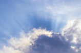 Soft radiant light filtering through translucent angel wings amidst a serene blue sky.