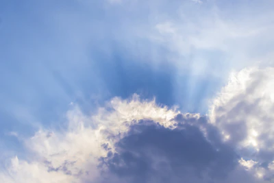 Soft radiant light filtering through translucent angel wings amidst a serene blue sky.
