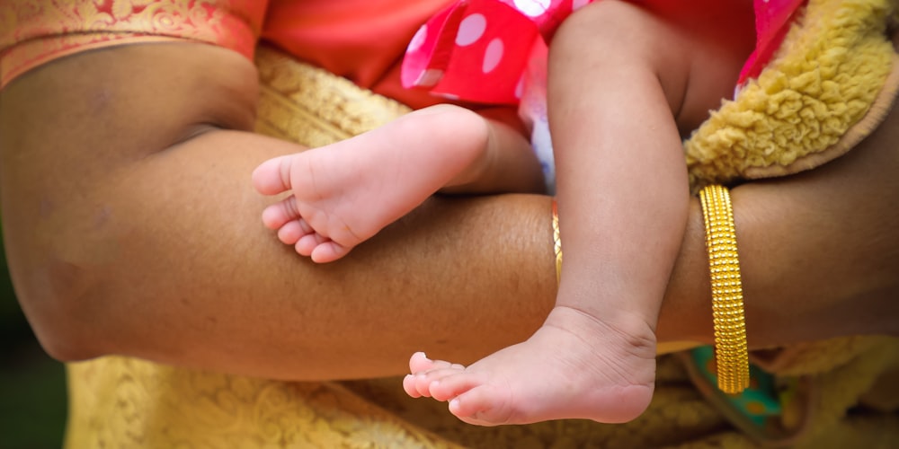um close-up das mãos de uma mulher segurando os pés de um bebê