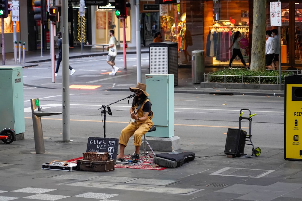 a person sitting on a sidewalk with luggage