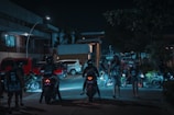 An urban anime-inspired scene of a group of riders gathered around a glowing mystical symbol painted on the street.