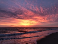 A vibrant sunset over a peaceful beach with gentle waves.