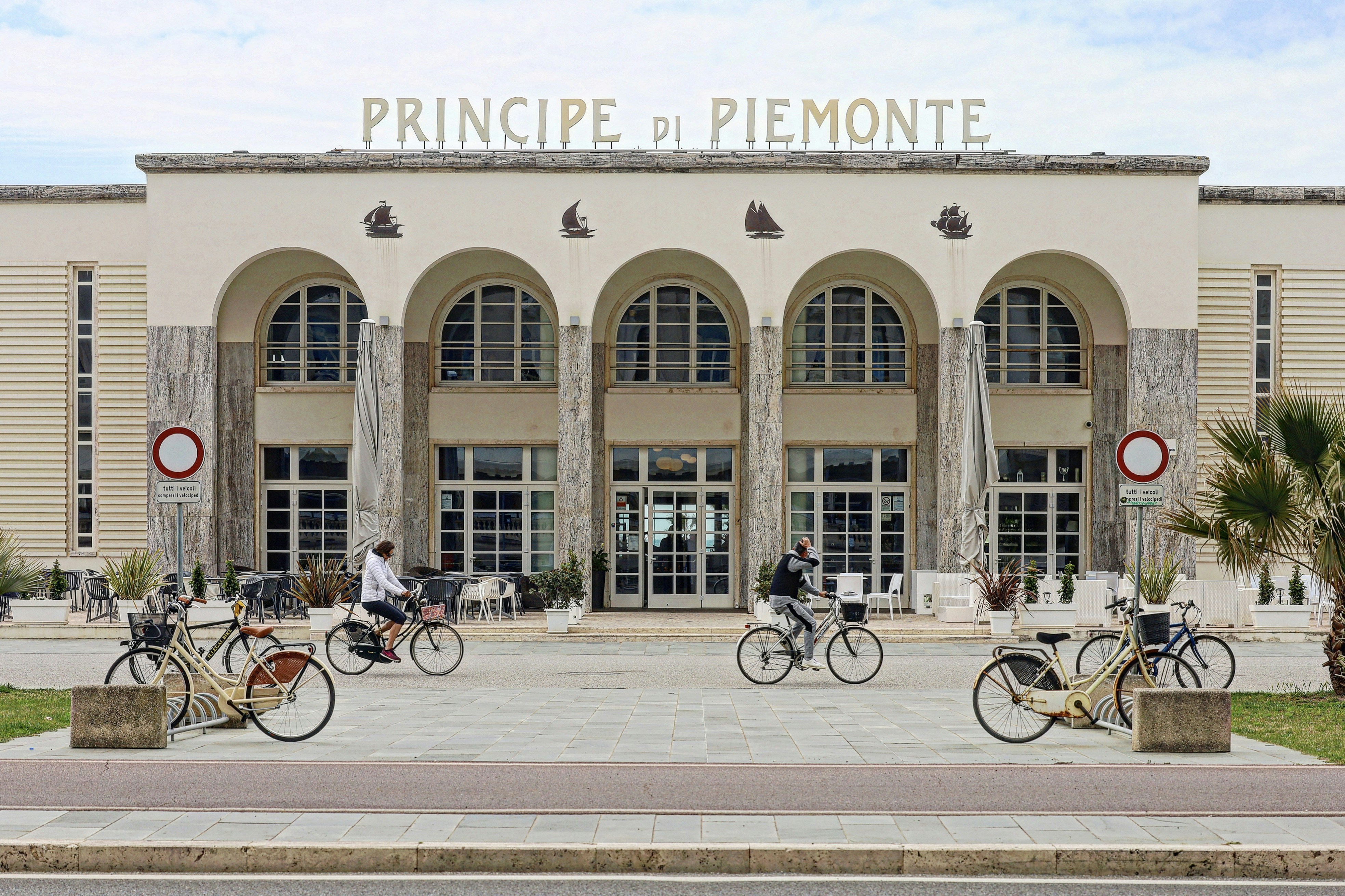 a couple of people riding bikes in front of a building