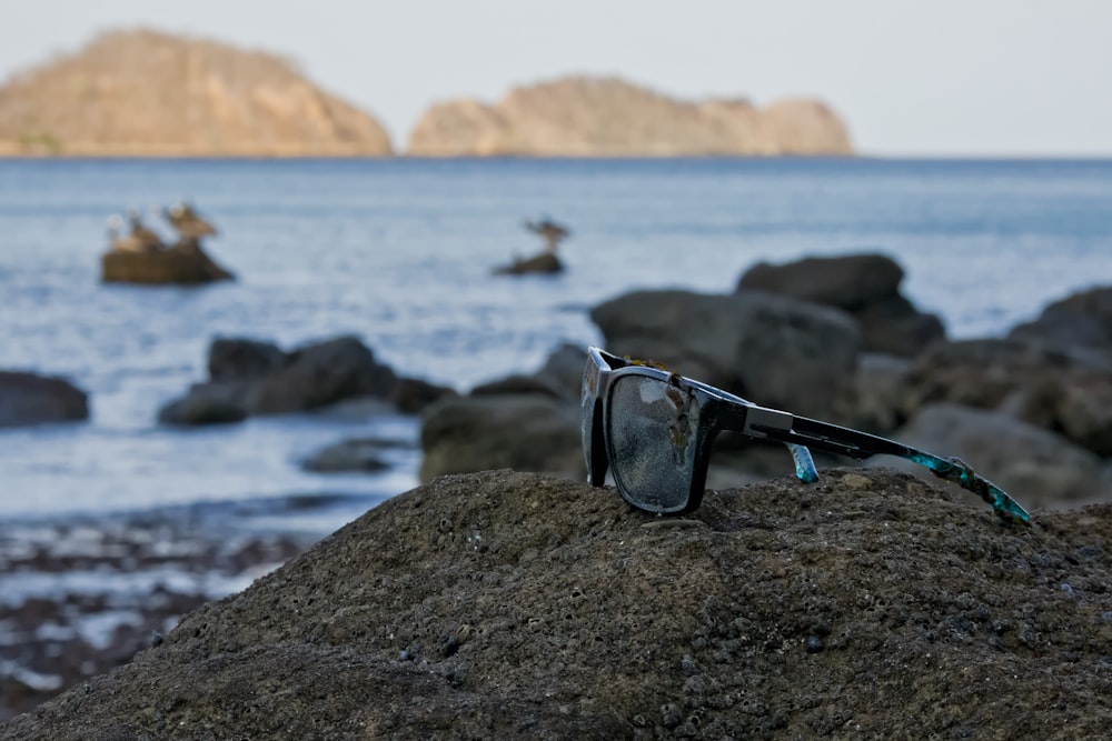 a pair of sunglasses on a rock by the water