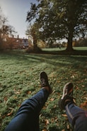a person's legs and feet in a grassy area with trees