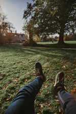a person's legs and feet in a grassy area with trees
