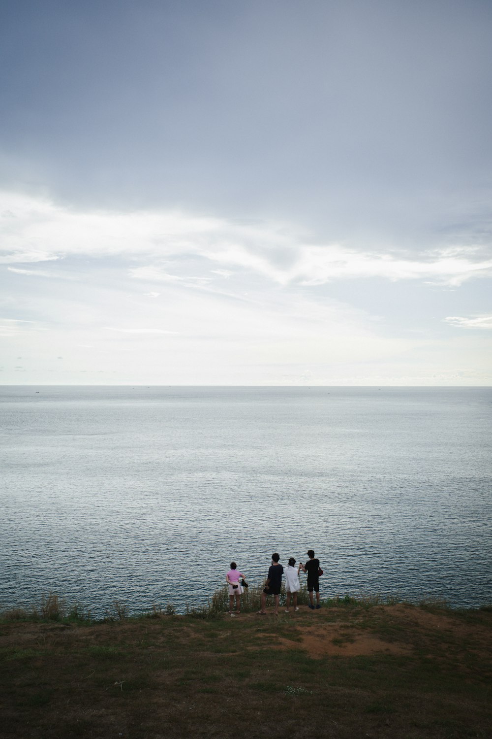 a group of people standing on a hill by a body of water