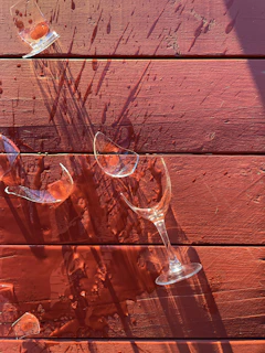 Close-up of colorful shattered drinking glass pieces scattered on a wooden table.