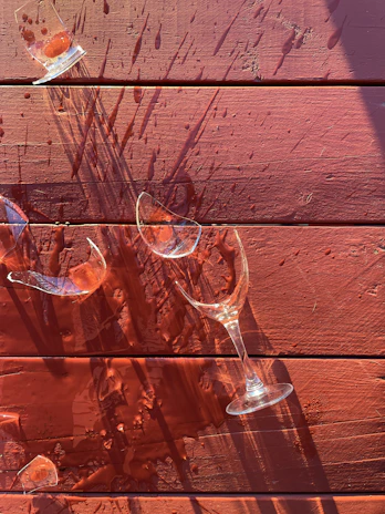 Close-up of colorful shattered drinking glass pieces scattered on a wooden table.
