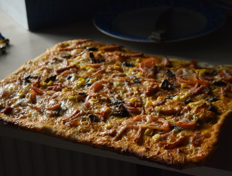 Flatbread topped with tomatoes and olives on a wooden table