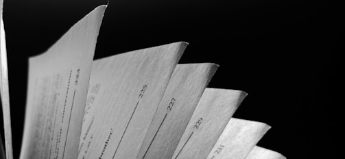 Several pages of a book or manual are spread out, each with visible numbers on the edge, against a dark background.