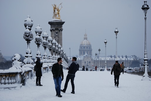 a group of people standing in the snow with a building in the background
