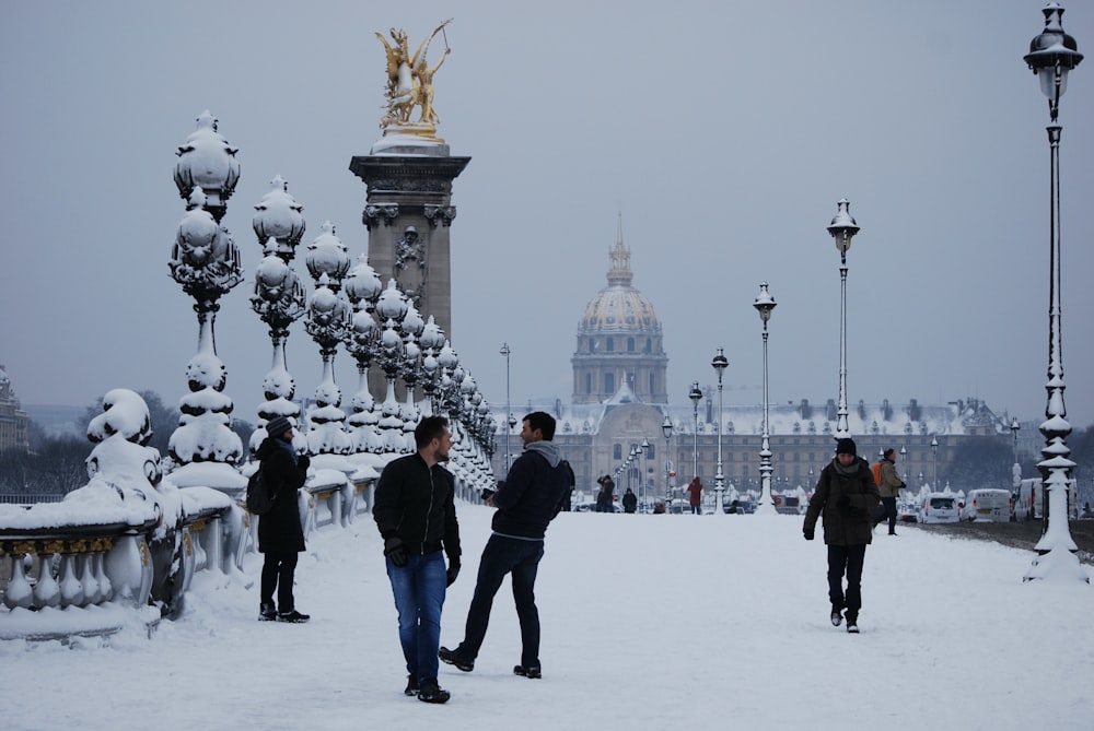 a group of people standing in the snow with a building in the background
