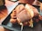 A close-up of a crispy fried chicken sandwich with a golden bun, served in a dark tray. The sandwich is filled with fried chicken pieces, lettuce, and sauce, placed on a wooden table with a warm, inviting ambiance.
