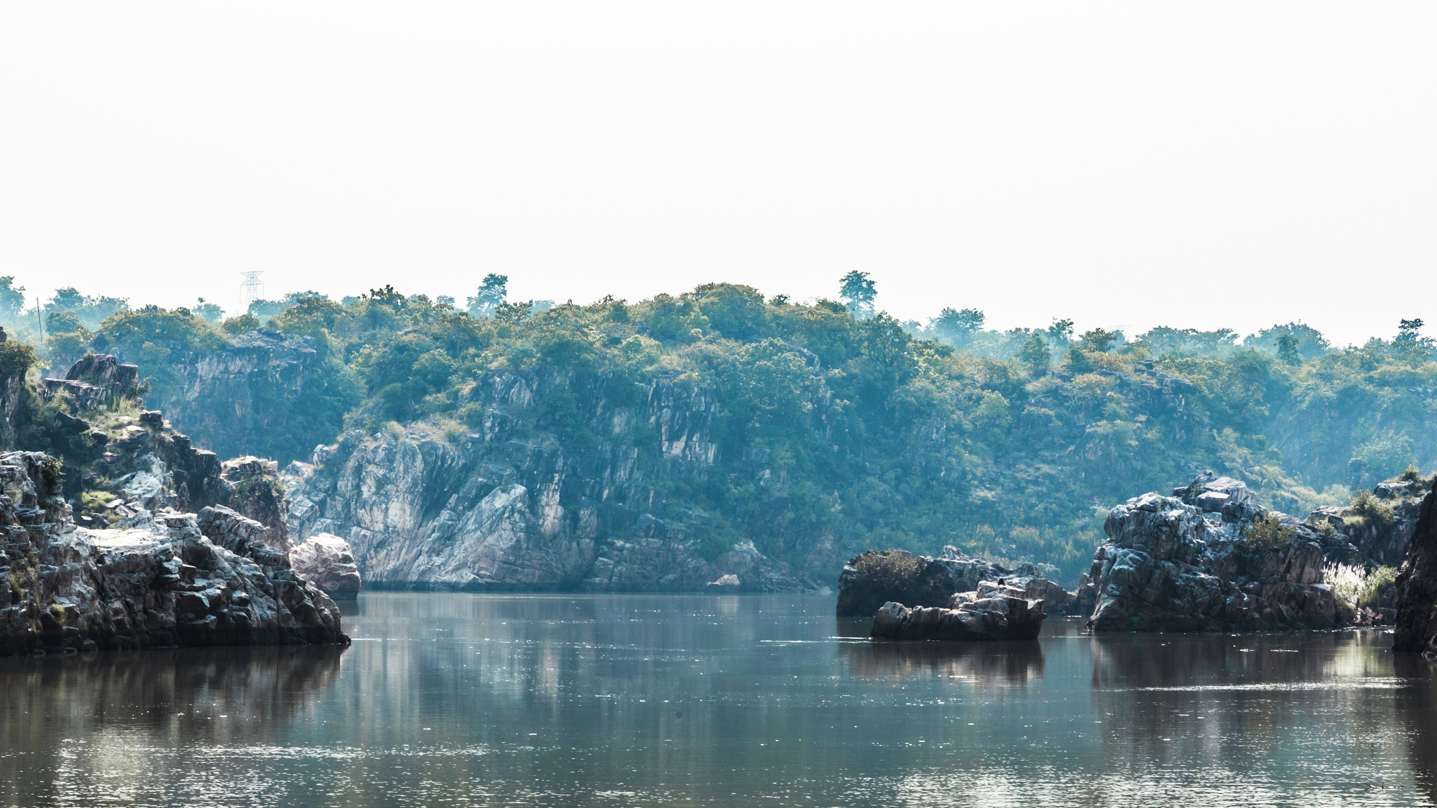 a body of water with a rocky hill in the background, 