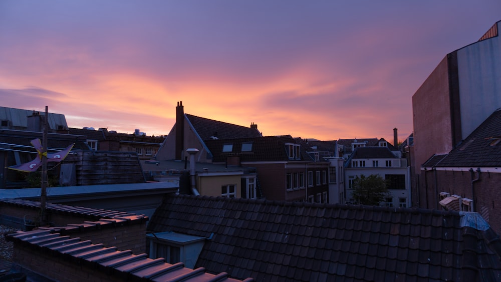 a group of rooftops with a pink and purple sky
