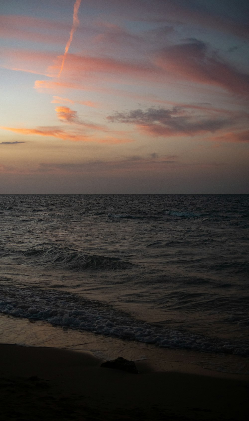 a beach with waves and a sunset