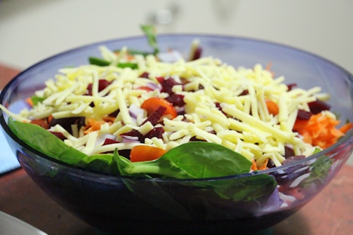 A person preparing a healthy salad with colorful ingredients.