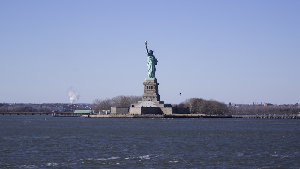 a statue on a pedestal by the water