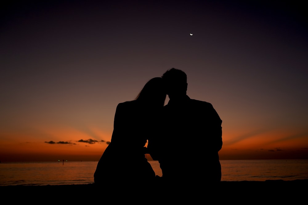 a man and woman kissing at sunset
