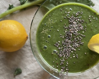 a glass bowl with a green liquid and a leafy green plant