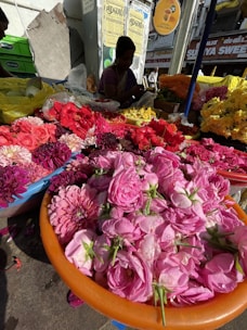 A vibrant standing flower board with colorful ribbons and fresh blossoms displayed at an outdoor market