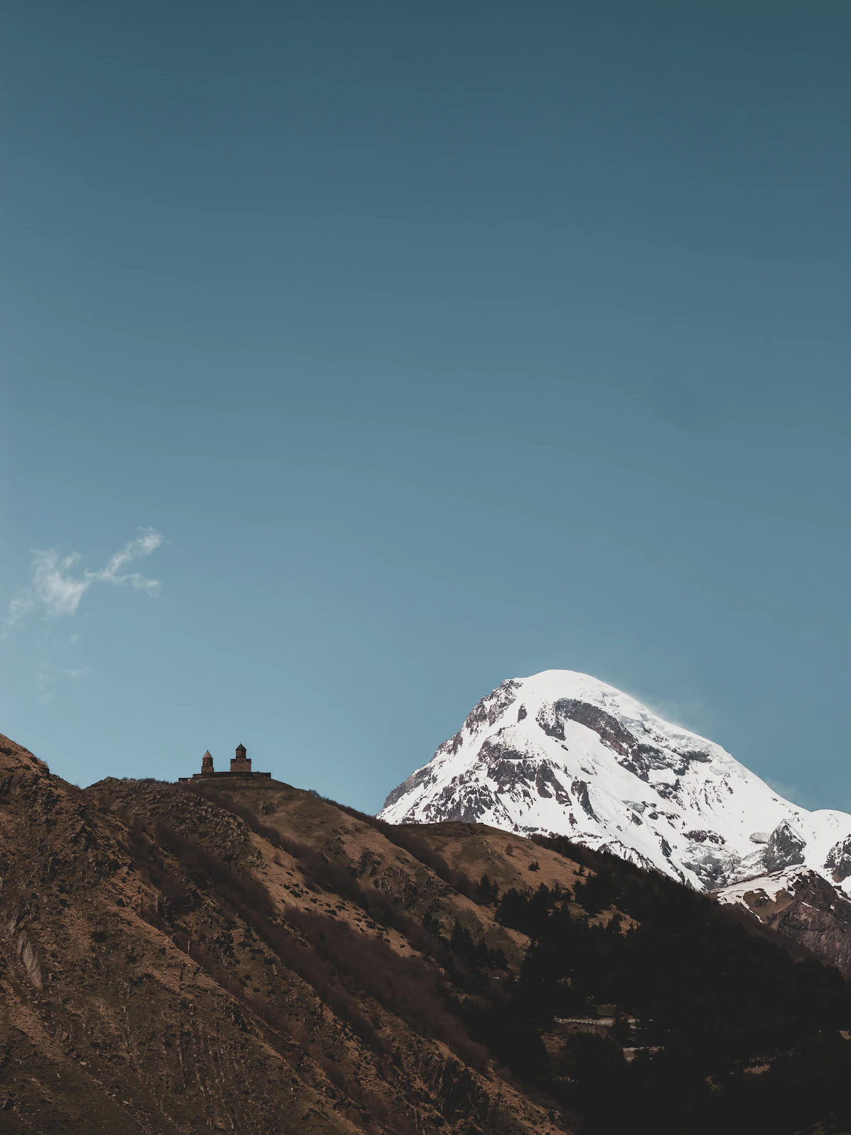 Gergeti Trinity Church silhouetted on a ridge before the snow-capped peak of Mount Kazbek