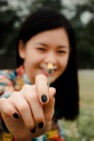 Close-up of a joyful woman holding a flower, her eyes shining with renewed strength.