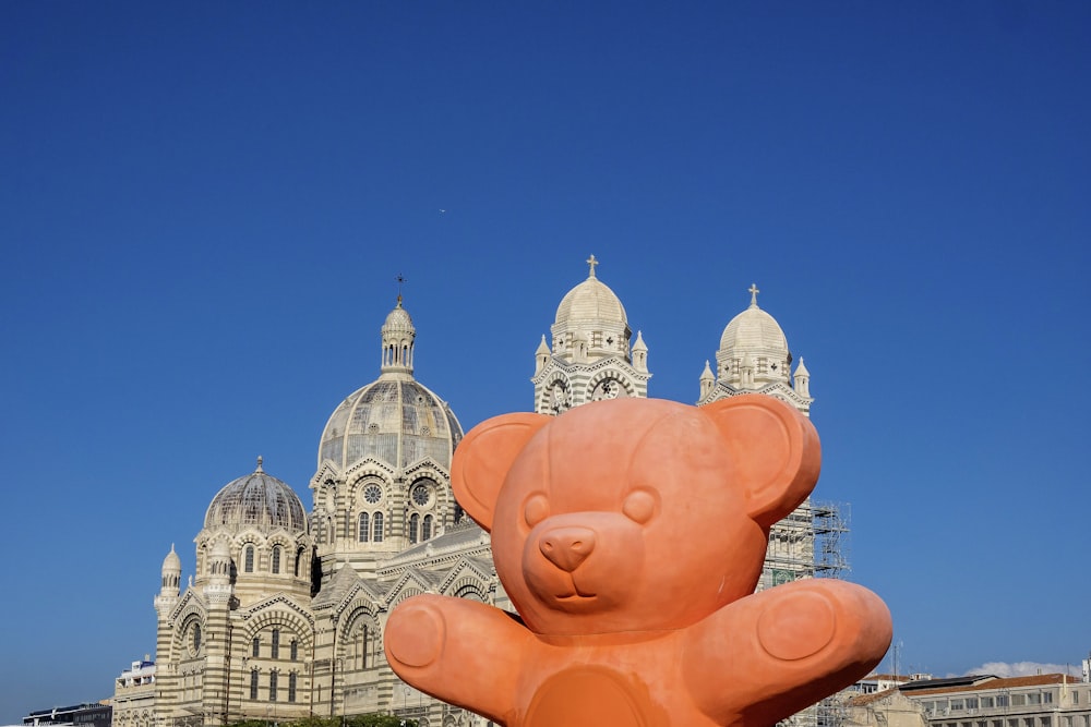 a large orange toy in front of a large building